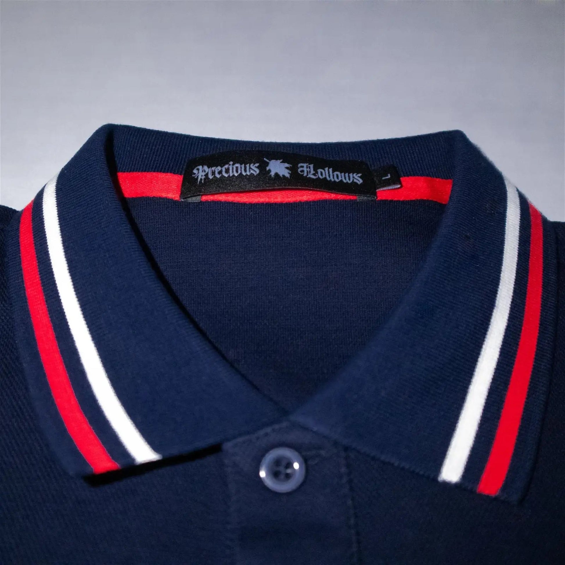 Close up of a navy blue collar with red and white stripes featuring a neck label.#color_navy