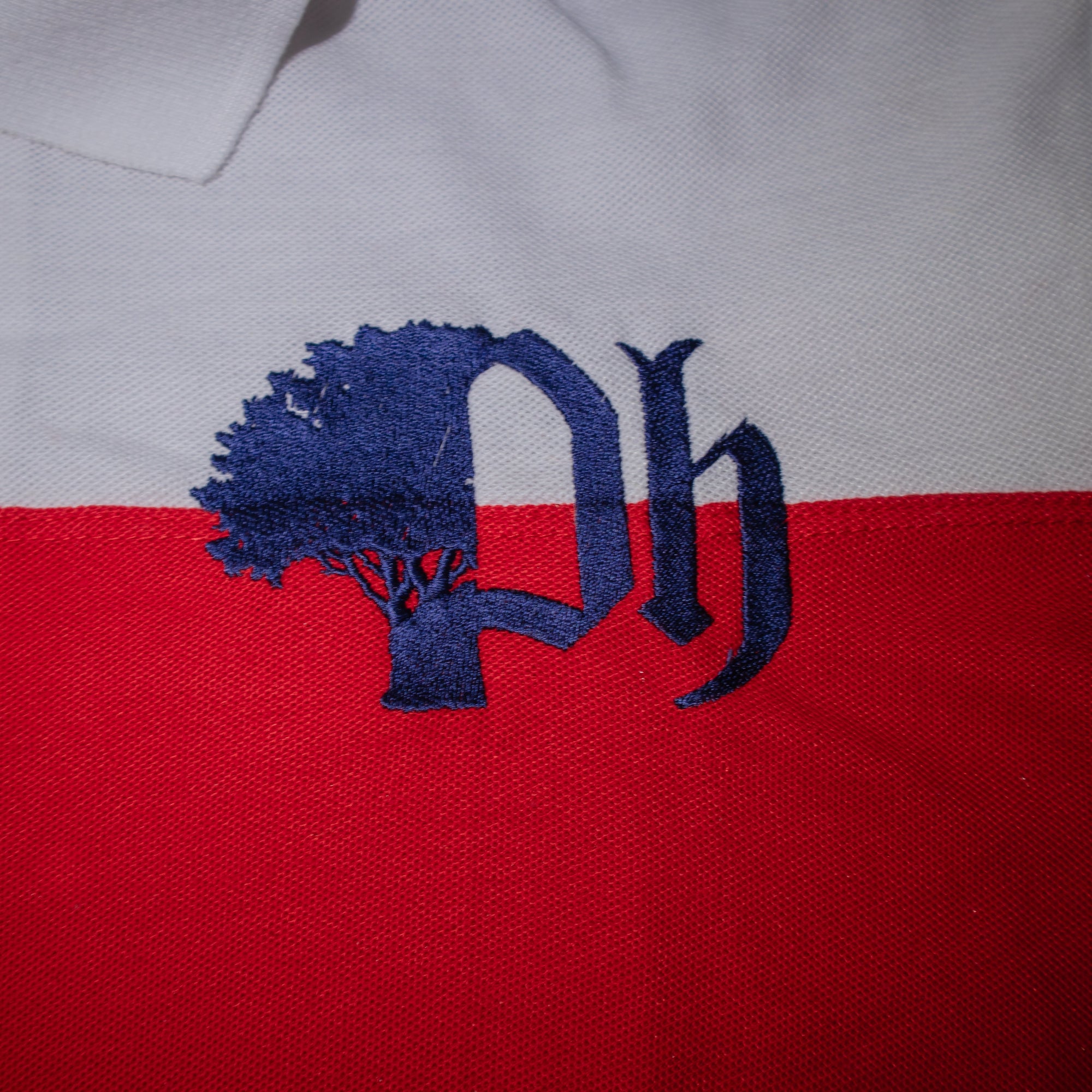 Close-up of a logo on a polo shirt with striped red and white fabric.