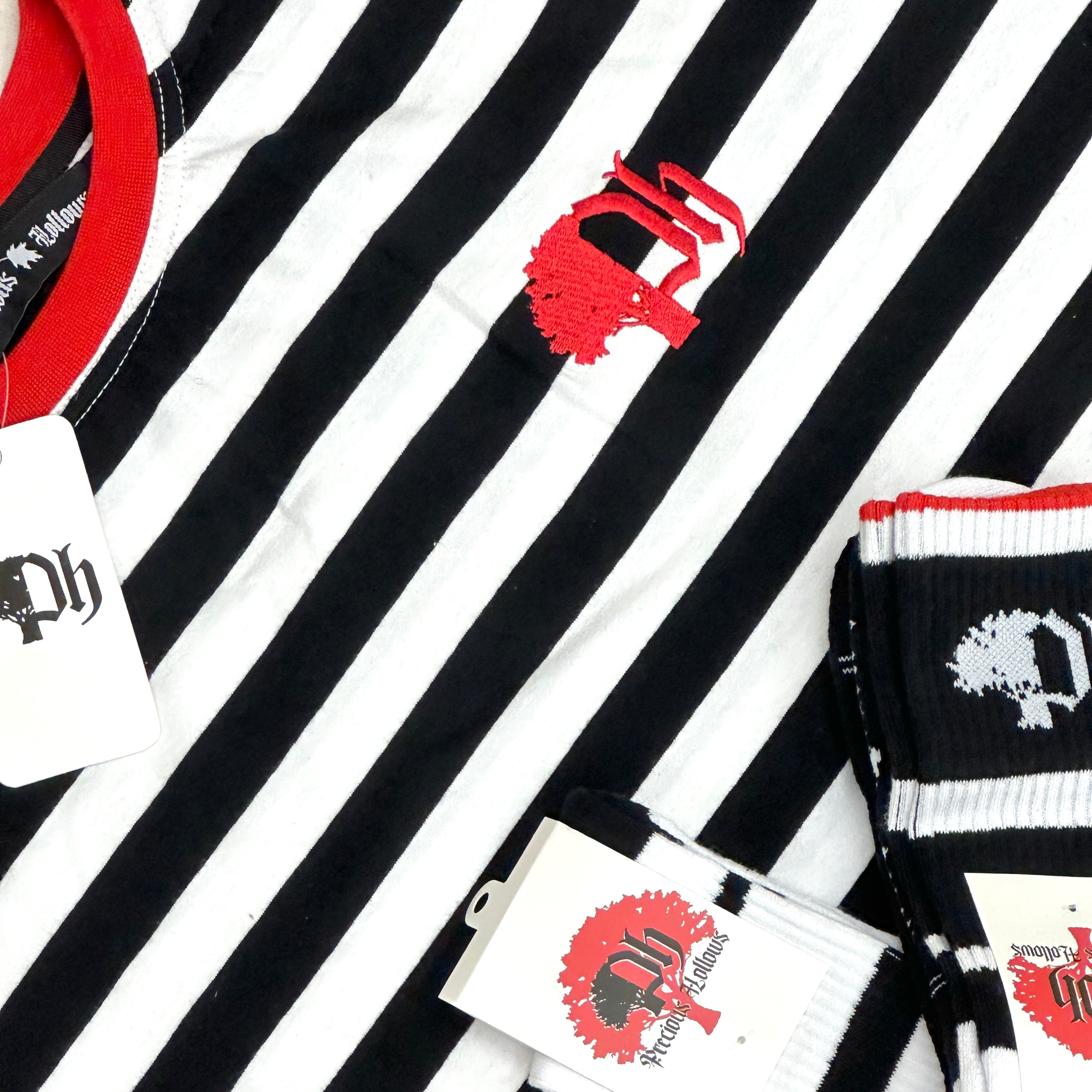 Close up of cotton t-shirt with black and white horizontal stripes, featuring red collar and logo on the chest.