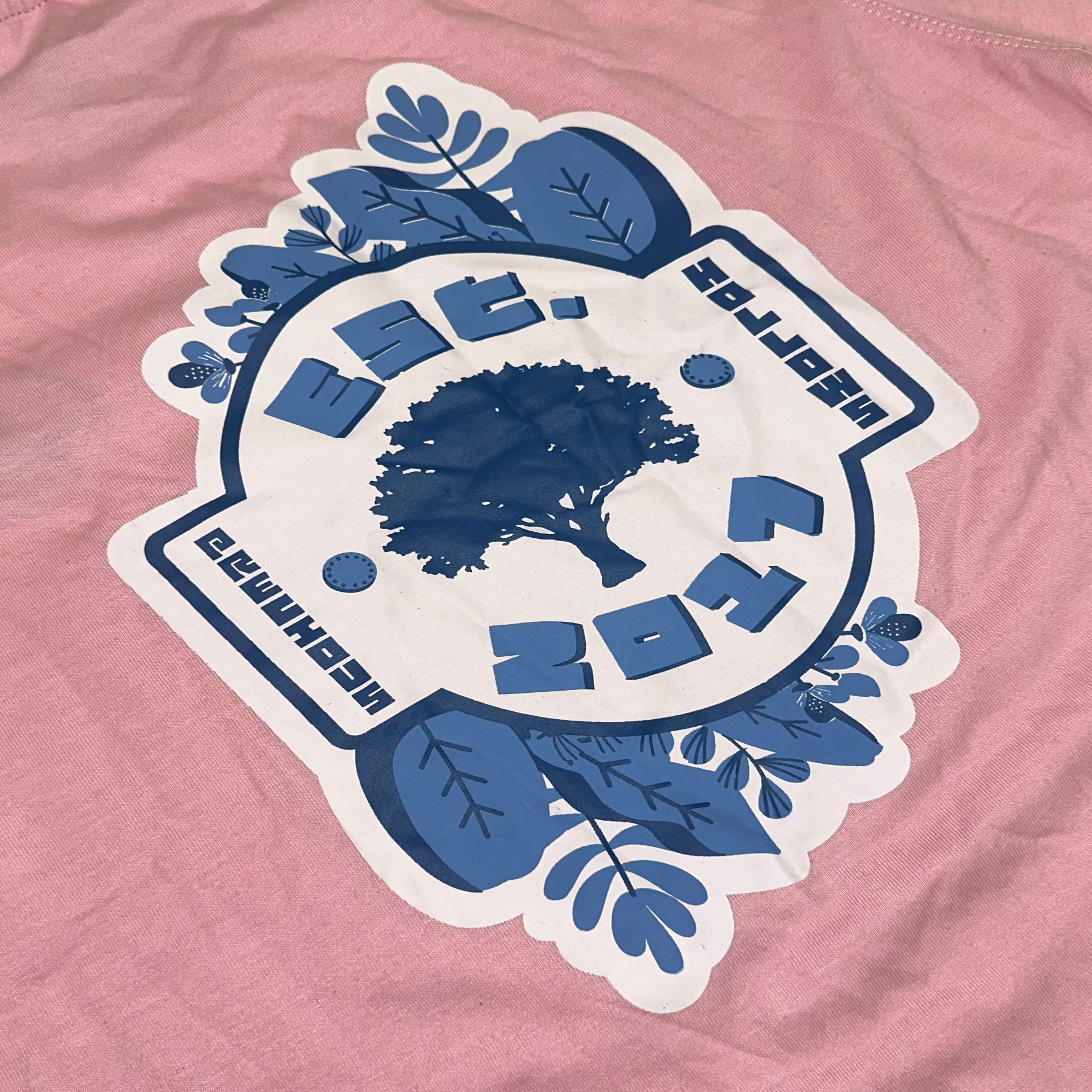 Blue and white logo on a pink shirt.