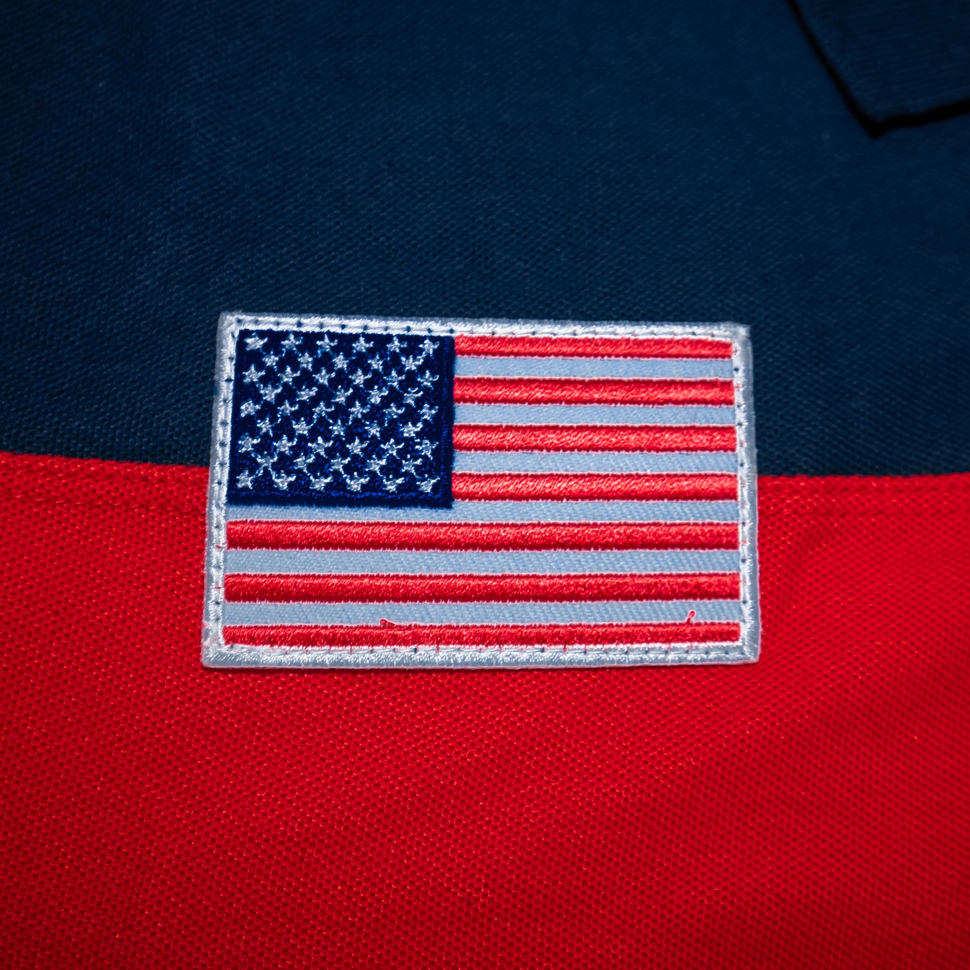 American flag patch on navy blue and red fabric.#color_navy-stripes