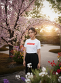 Woman standing in a garden with cherry blossom trees and colorful flowers