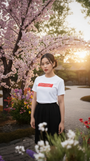 Woman standing in a garden with cherry blossom trees and colorful flowers