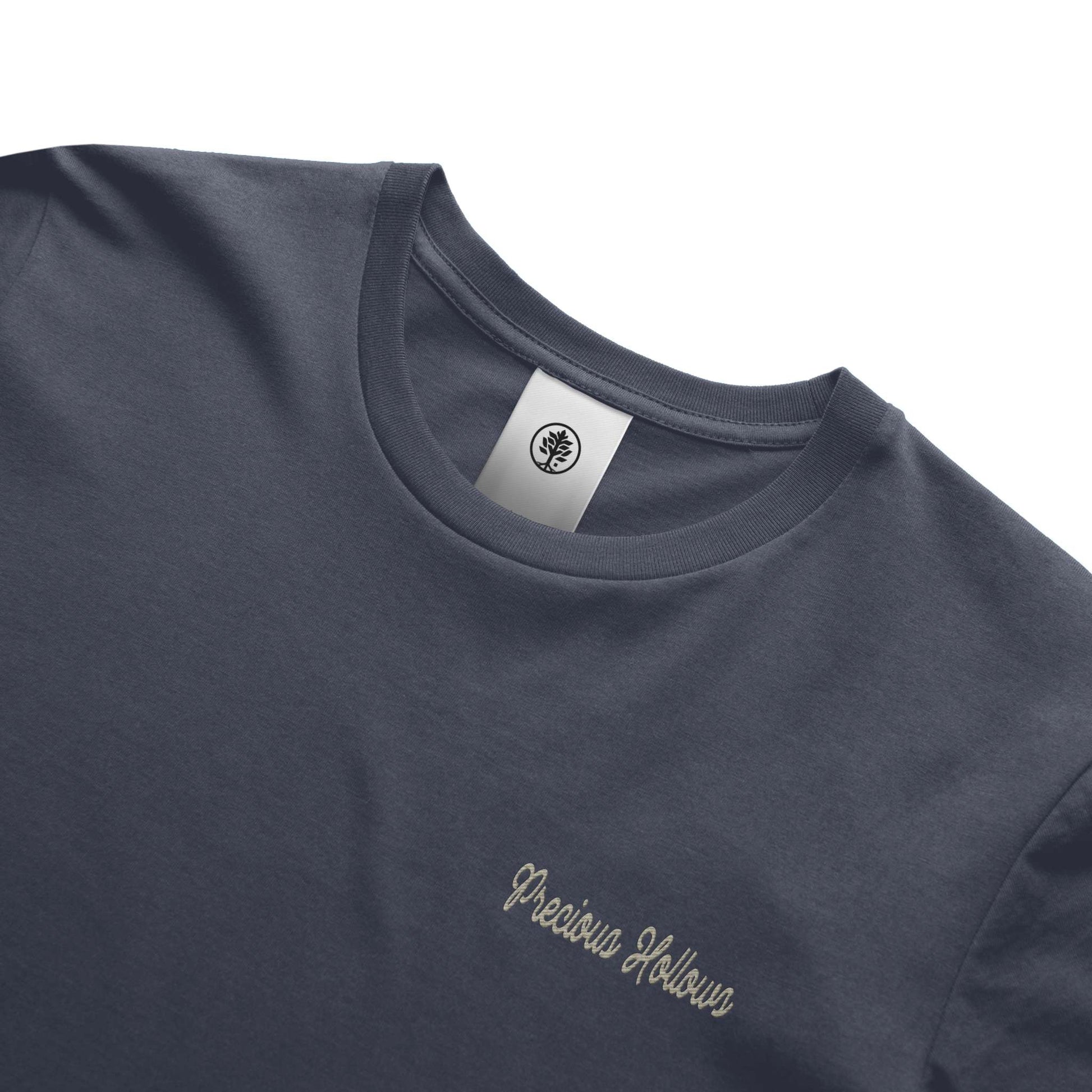 Navy blue t-shirt with 'Precious Hollows' embroidery and a brand label on a white background