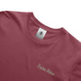 Close-up of a maroon t-shirt with 'Precious Hollows' text and a brand tag on a white background