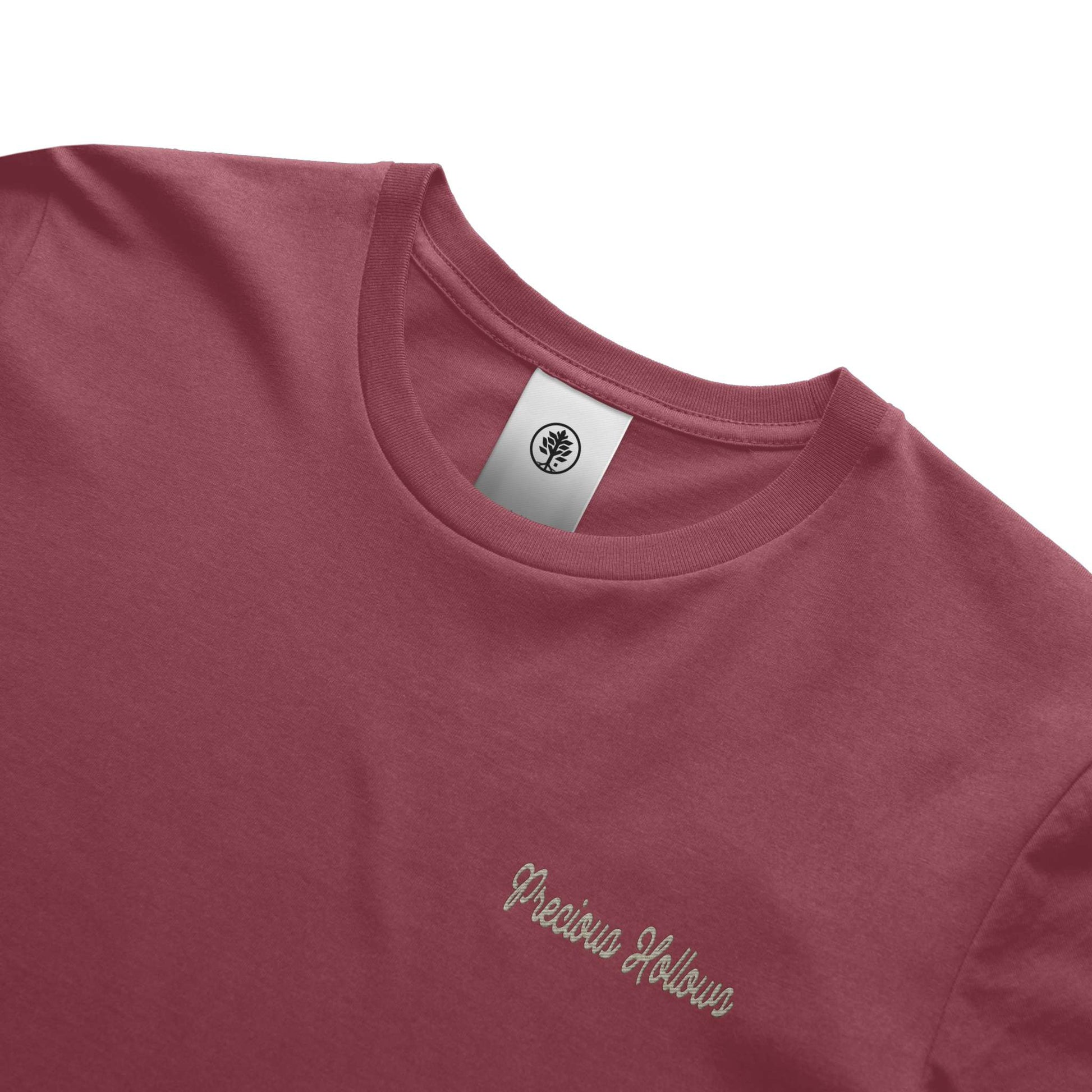 Close-up of a maroon t-shirt with 'Precious Hollows' text and a brand tag on a white background