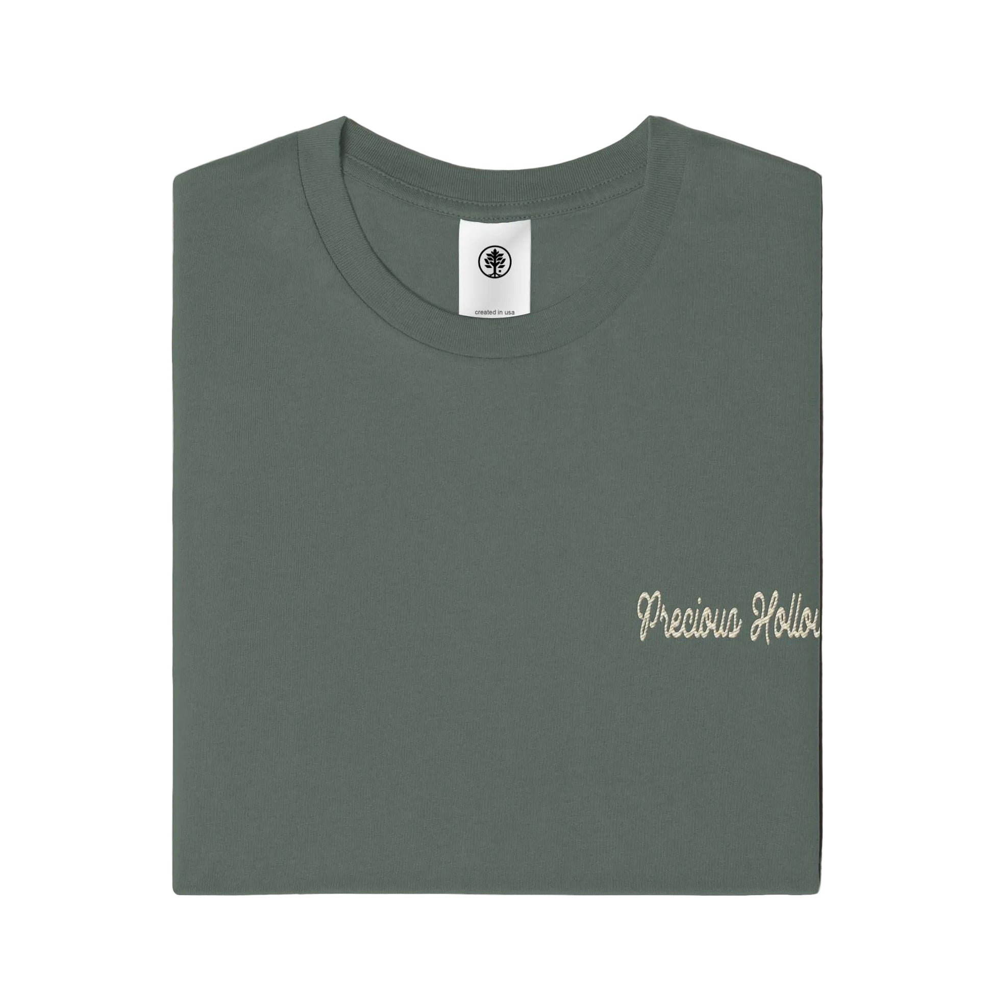 Folded green t-shirt with 'Precious Hollows' text on a white background