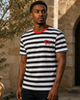 Model wearing the Precious Hollows District Stripe Tee in a warm courtyard